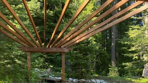 Una estructura de pergola de fusta sobre una petita cascada en una zona boscosa.