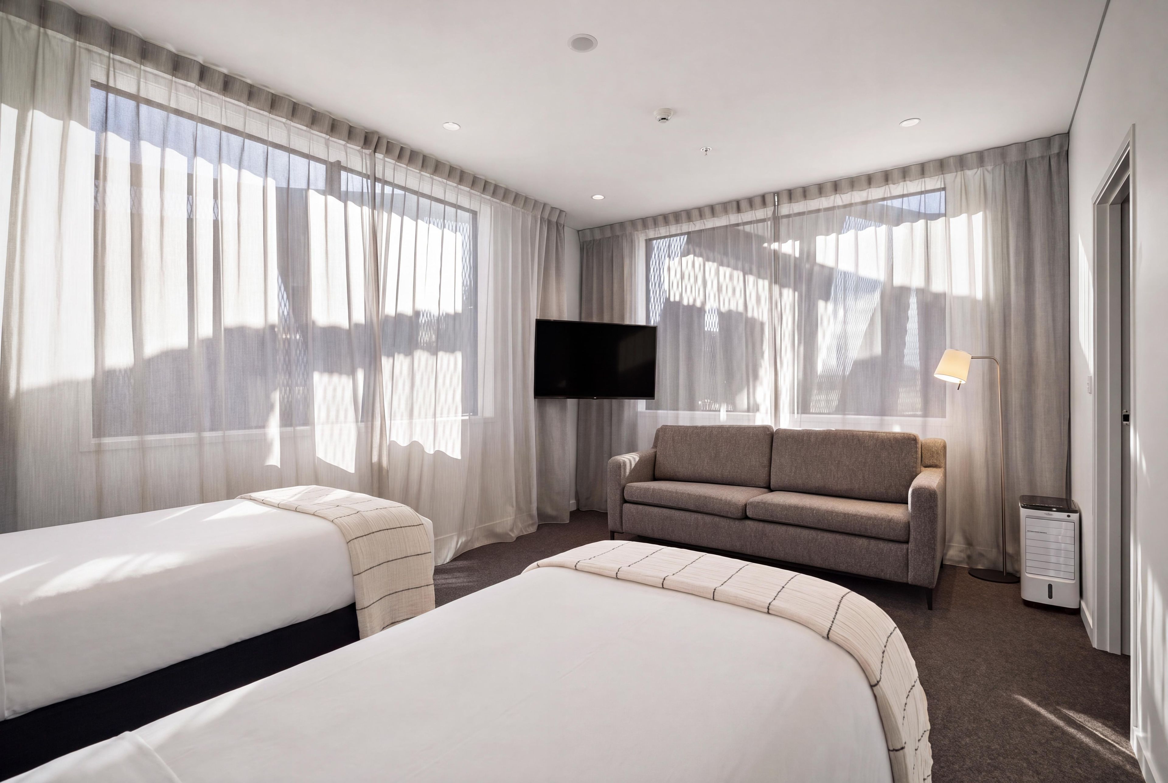 Una habitación de hotel con dos camas, un sofá, un televisor y un calentador.