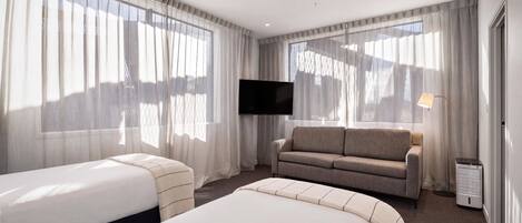 Una habitación de hotel con dos camas, un sofá, un televisor y un calentador.