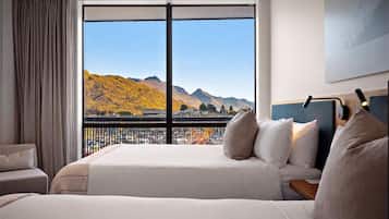A hotel room with a large window offering a view of mountains and a parking lot.