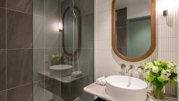 A modern bathroom with a glass-enclosed shower, a white sink, and a mirror with a wooden frame.