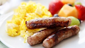 A plate with scrambled eggs, sausages, and fresh fruit. - Sudima Queenstown Five Mile (Queenstown)