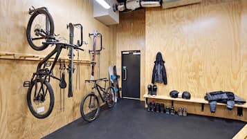 A room with wooden walls, a black carpet, a bench with helmets, and bicycles mounted on the wall.