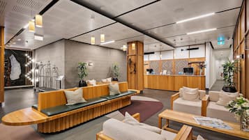 A modern lobby with seating areas, a reception desk, and a wall with a unique pattern.
