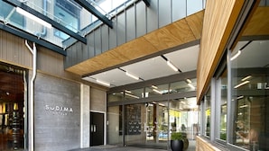 A modern hotel entrance with a glass facade, a wooden ceiling, and a visible outdoor area. - Sudima Queenstown Five Mile (Queenstown)