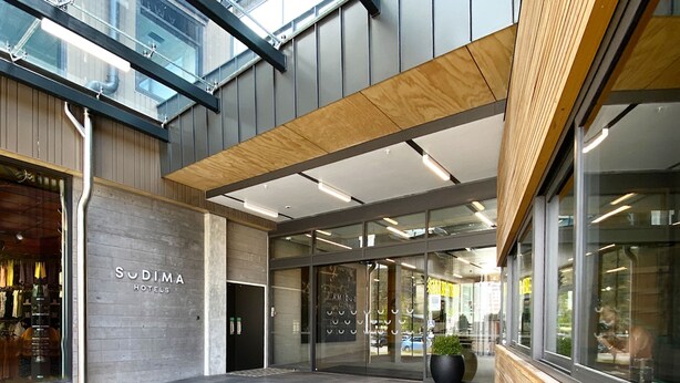 A modern hotel entrance with a glass facade, a wooden ceiling, and a visible outdoor area. - Sudima Queenstown Five Mile (Queenstown)