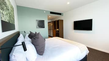 Habitación de hotel con cama, televisor de pantalla plana en la pared y un cuadro.