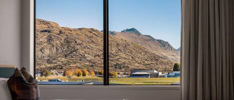 A hotel room with a large window offering a mountain view.