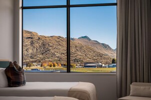 A hotel room with a large window offering a mountain view.