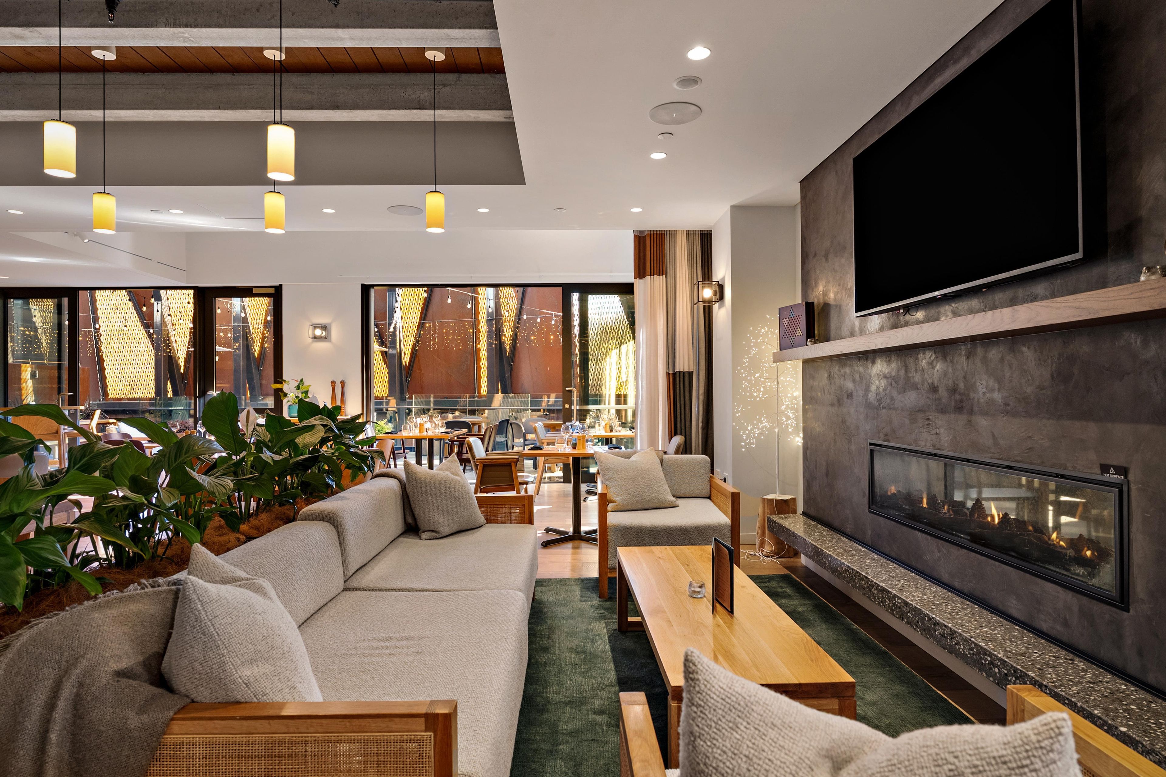A modern interior with a sofa, chairs, a fireplace, and a dining area.