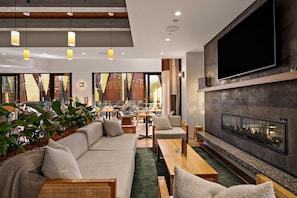 A modern interior with a sofa, chairs, a fireplace, and a dining area. - Sudima Queenstown Five Mile (Queenstown)