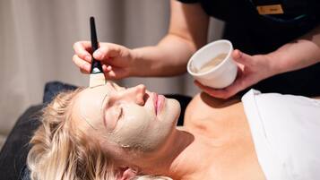 A person lying down with a facial mask being applied.