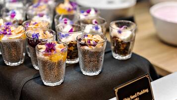A selection of chia seed puddings in clear glasses, some with fruit and edible flowers, on a table with a sign indicating the name.