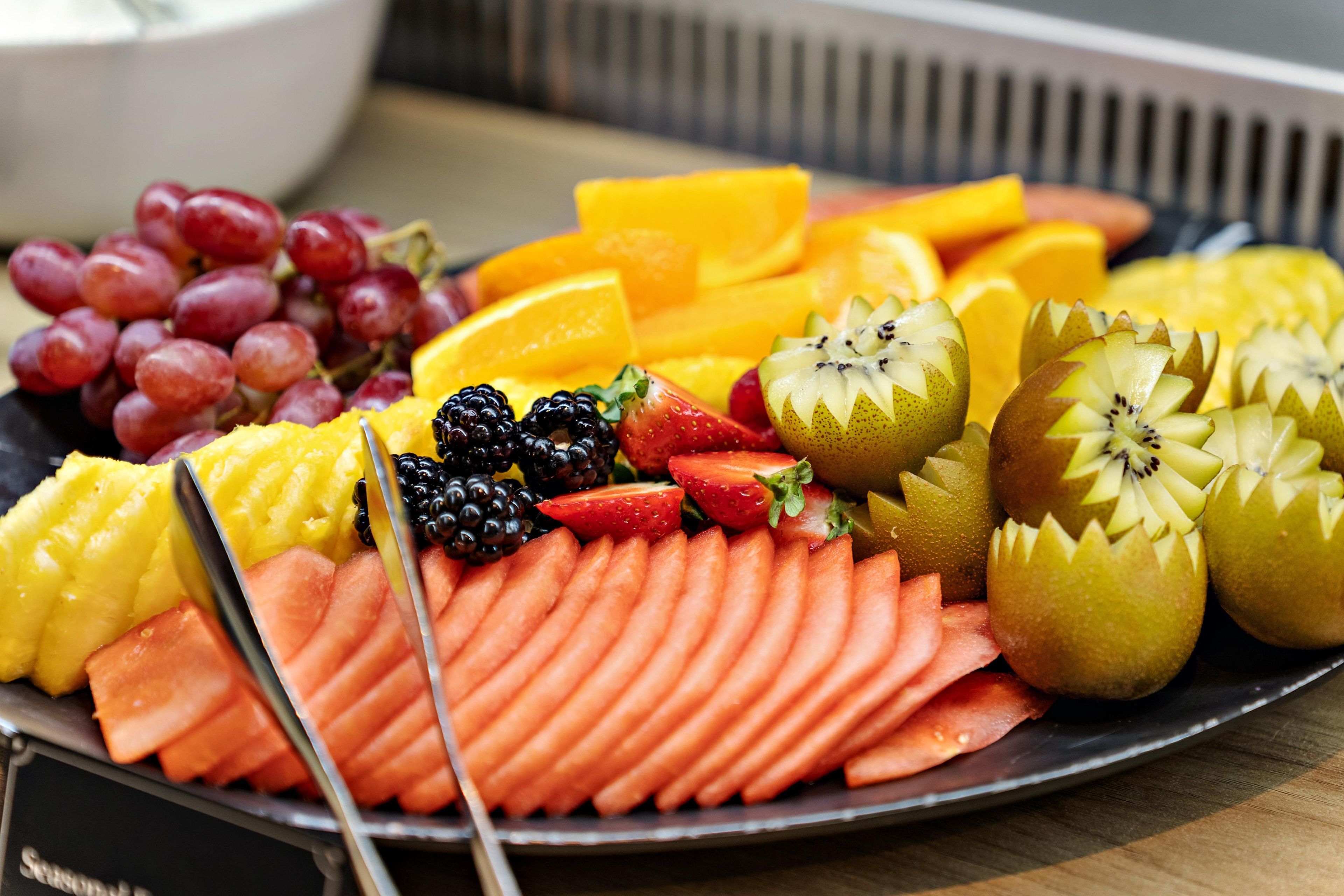 A fruit platter with sliced apples, oranges, grapes, strawberries, and watermelon.