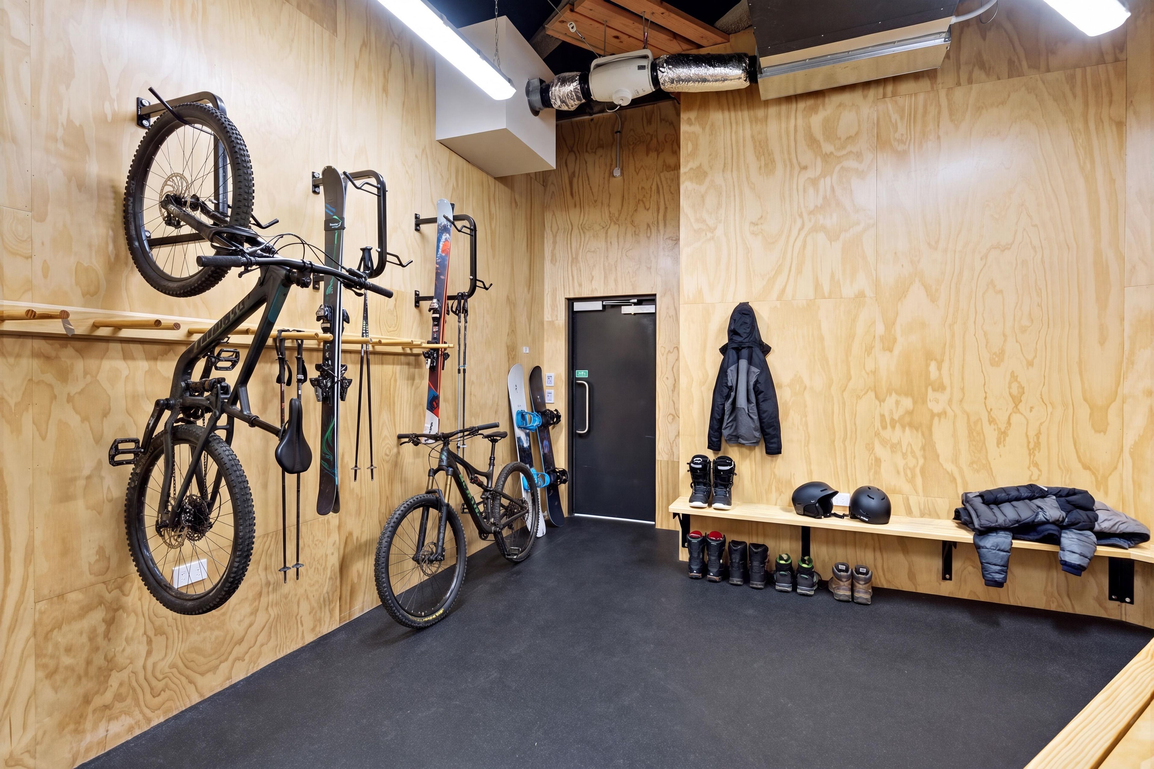 A room with wooden walls, a black carpet, a bench with helmets, and bicycles mounted on the wall.