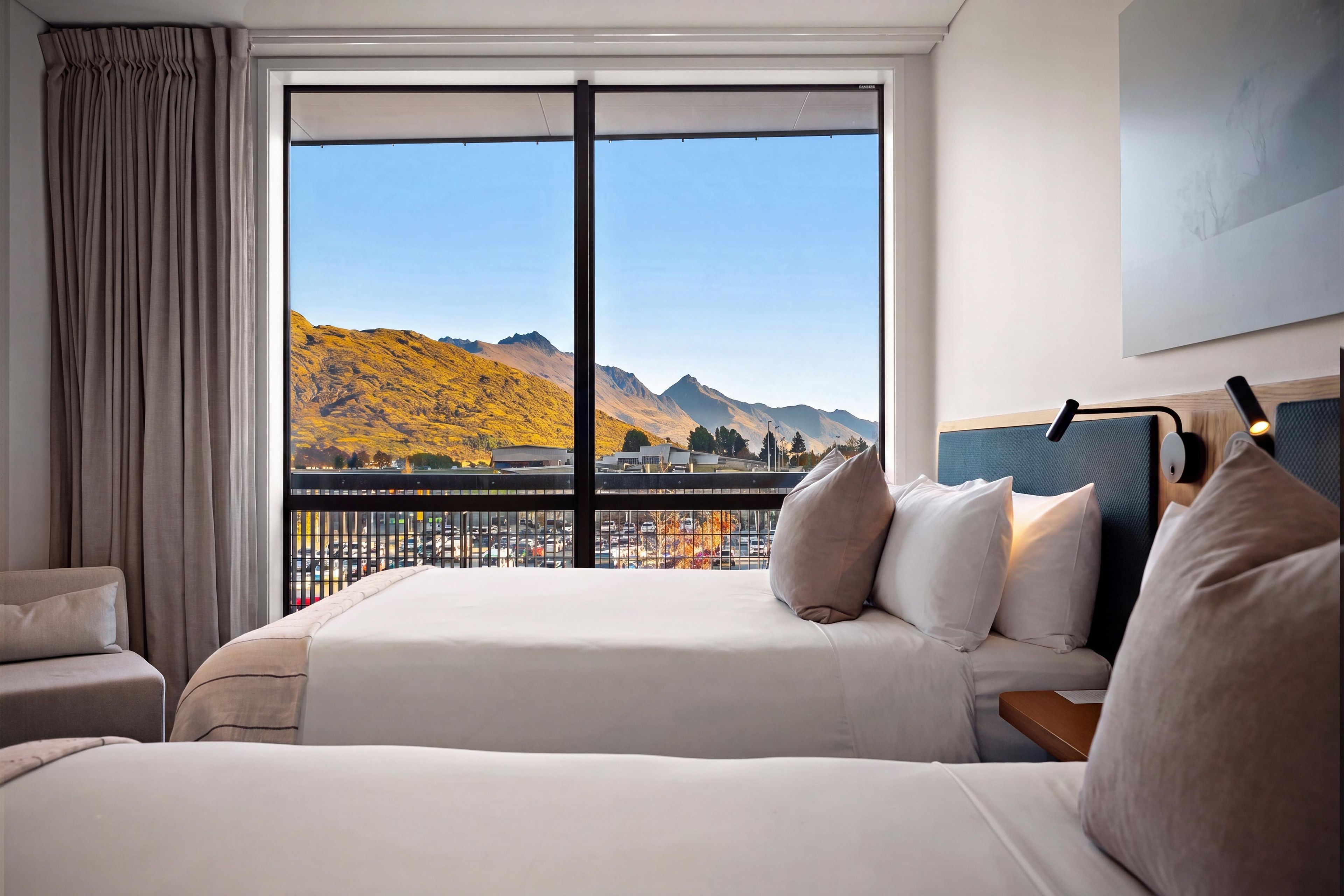 Une chambre d’hôtel dotée d’une grande fenêtre donnant sur les montagnes et un parking.