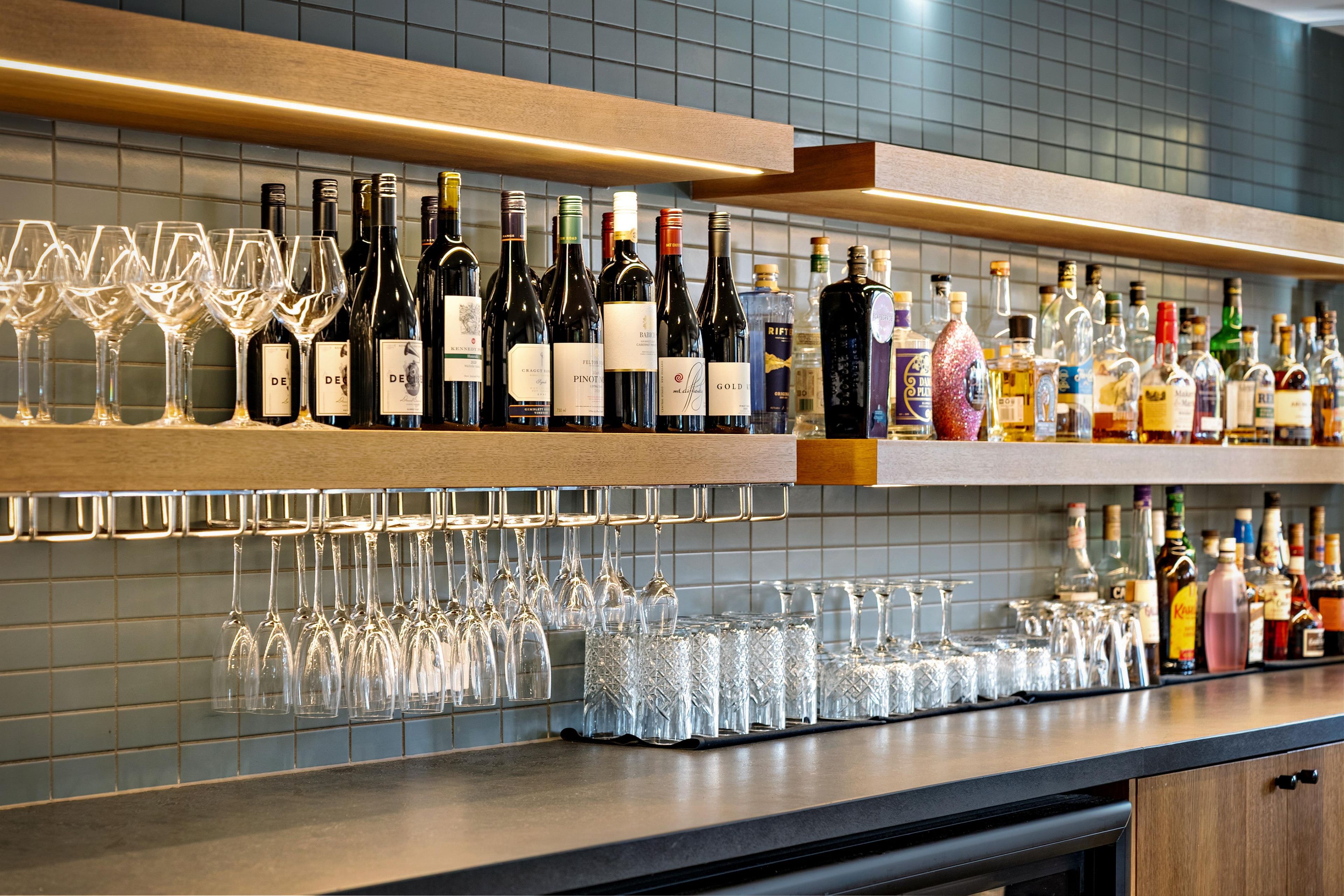 A bar area with shelves of wine bottles and glasses.