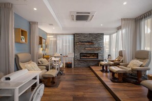 A modern living room with a fireplace, leather sofas, and a stone accent wall. - Sudima Queenstown Five Mile (Queenstown)
