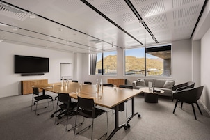 A conference room with a long table, chairs, a sofa, and a television on the wall.