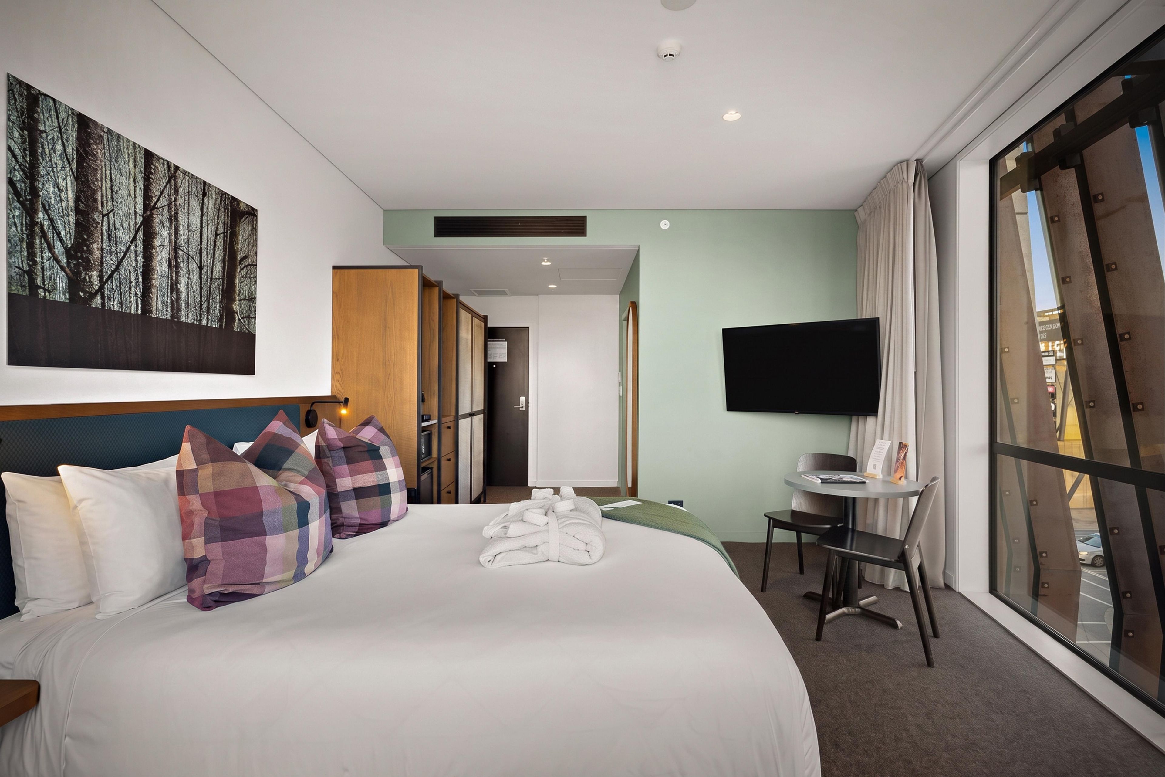 Een hotelkamer met een groot bed, een bureau, een televisie en uitzicht.
