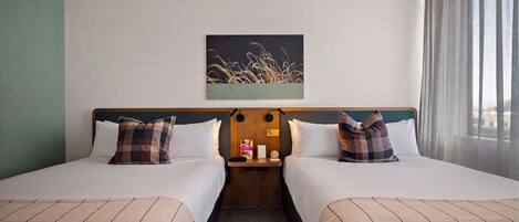 A hotel room with two beds, a nightstand, a painting, and a window with curtains.