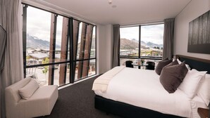 A hotel room with a large bed, a sofa, and a view of mountains through floor-to-ceiling windows. - Sudima Queenstown Five Mile (Queenstown)