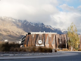 A building with a unique geometric facade and the 'five mile' logo, surrounded by mountains and a clear sky.