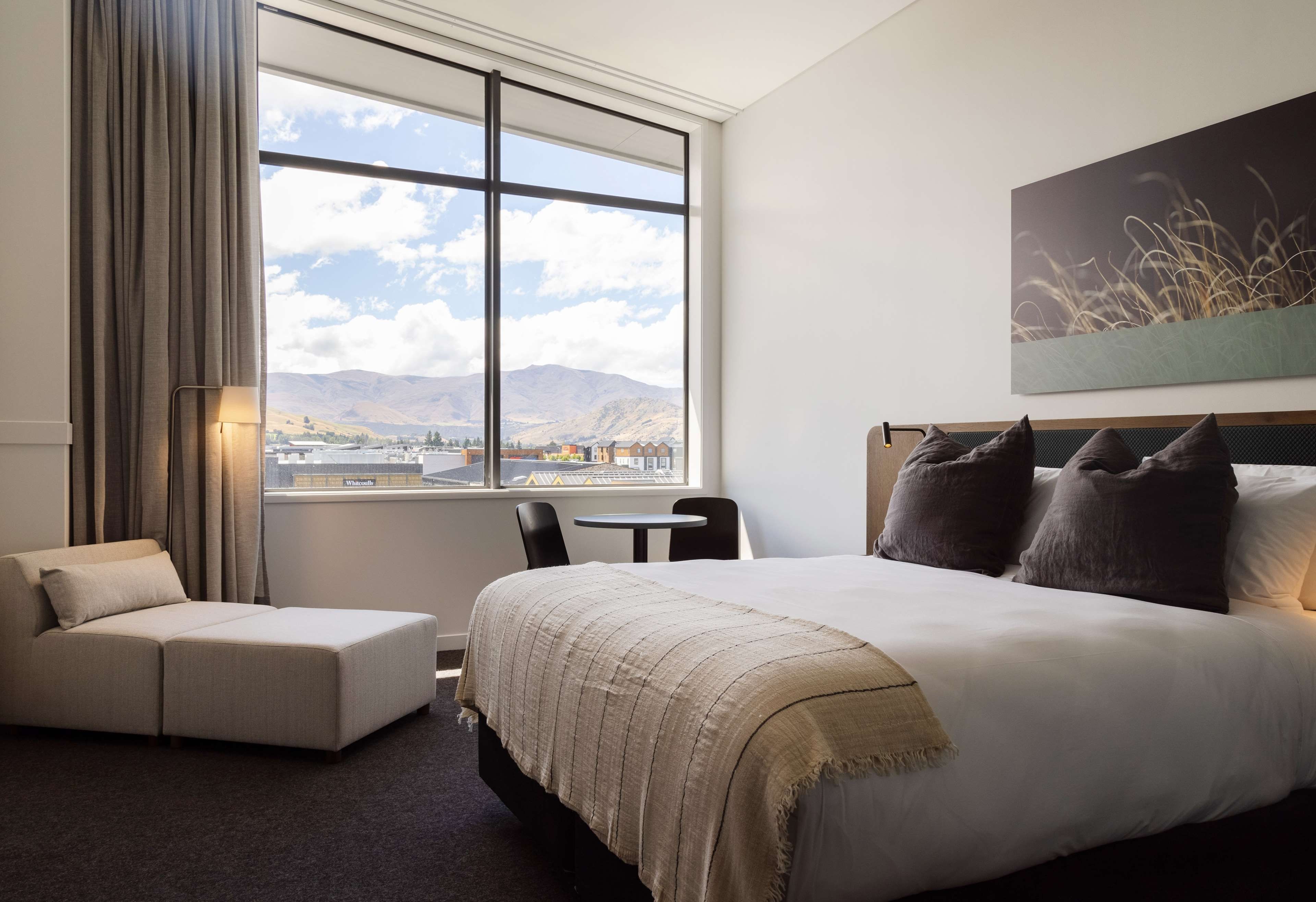 Habitación de hotel con una ventana grande, una cama, un sofá y una mesita.