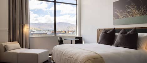 Habitación de hotel con una ventana grande, una cama, un sofá y una mesita.