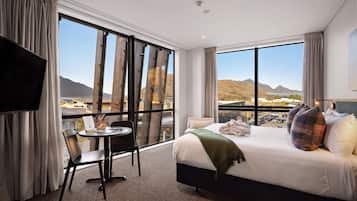 A hotel room with a large bed, a desk, and a TV.