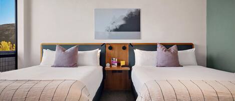 A hotel room with two beds, a nightstand, a lamp, and a painting on the wall.