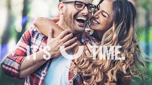 A couple embracing in a room with a large window, a bed, and a nightstand. - Sudima Queenstown Five Mile (Queenstown)