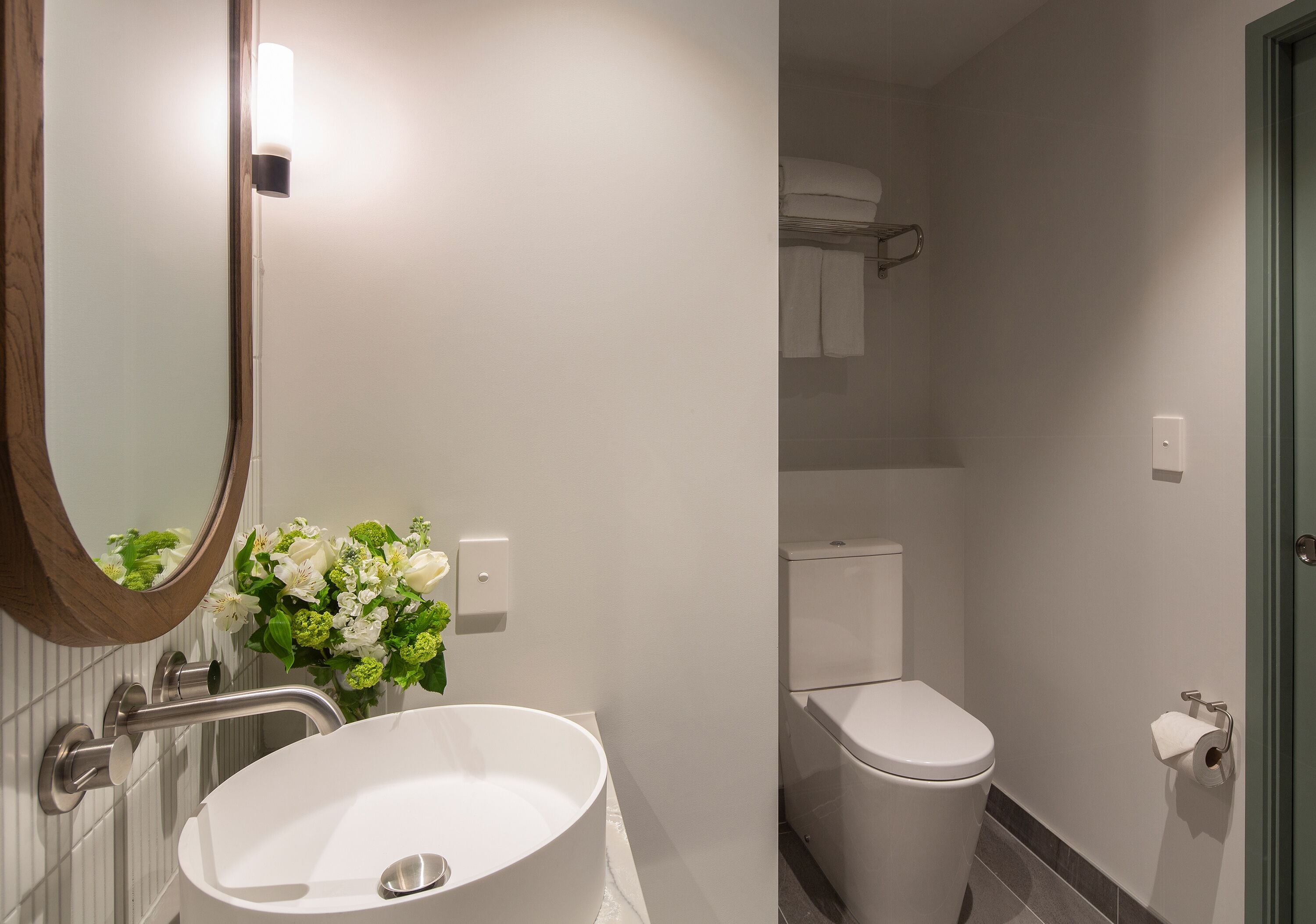 Un baño moderno con un lavamanos blanco, un espejo y un inodoro.
