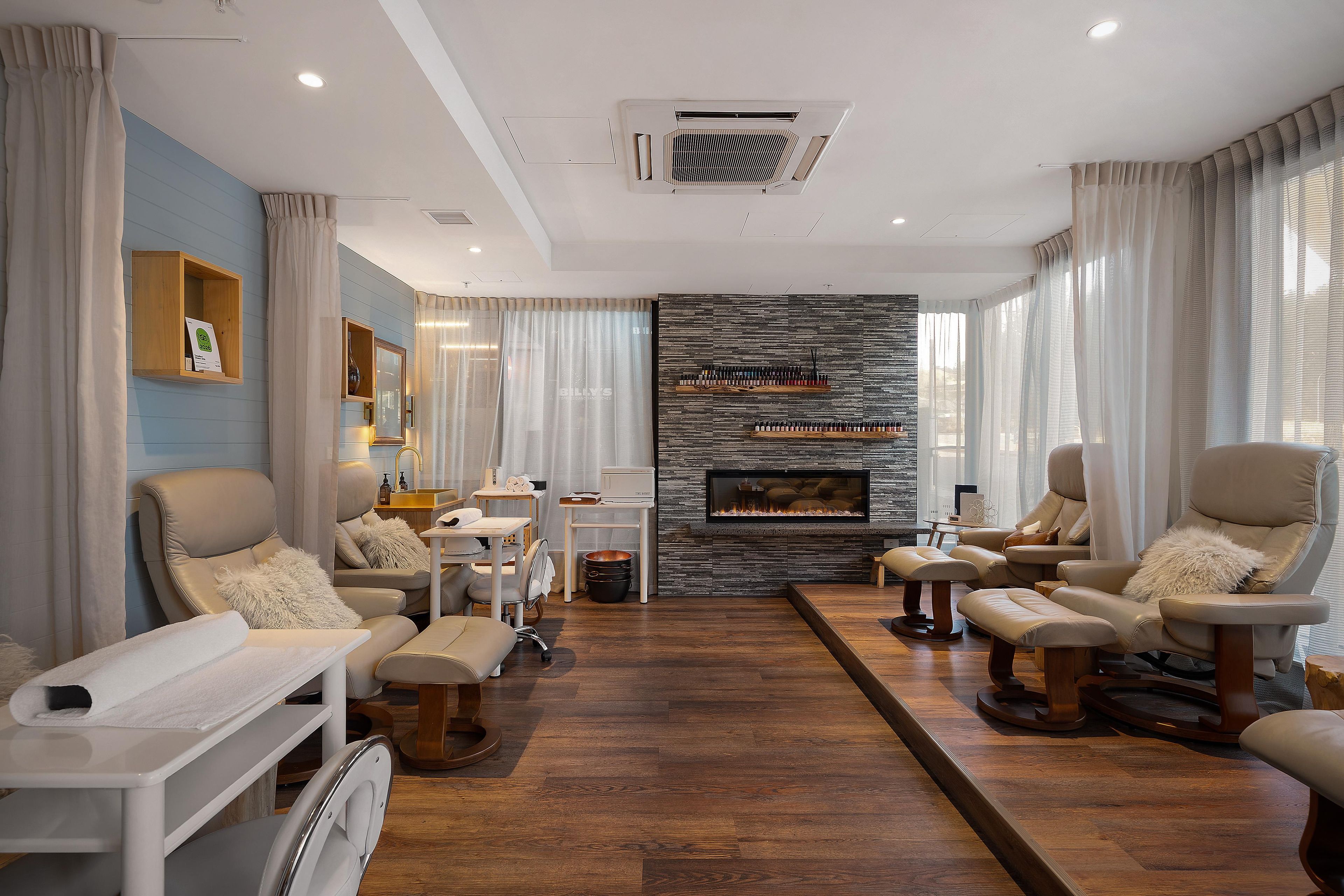 Una sala de estar moderna con chimenea, sofás de cuero y una pared de acento de piedra.
