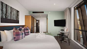 Habitación de hotel con una cama grande, escritorio, televisión y vistas al exterior.