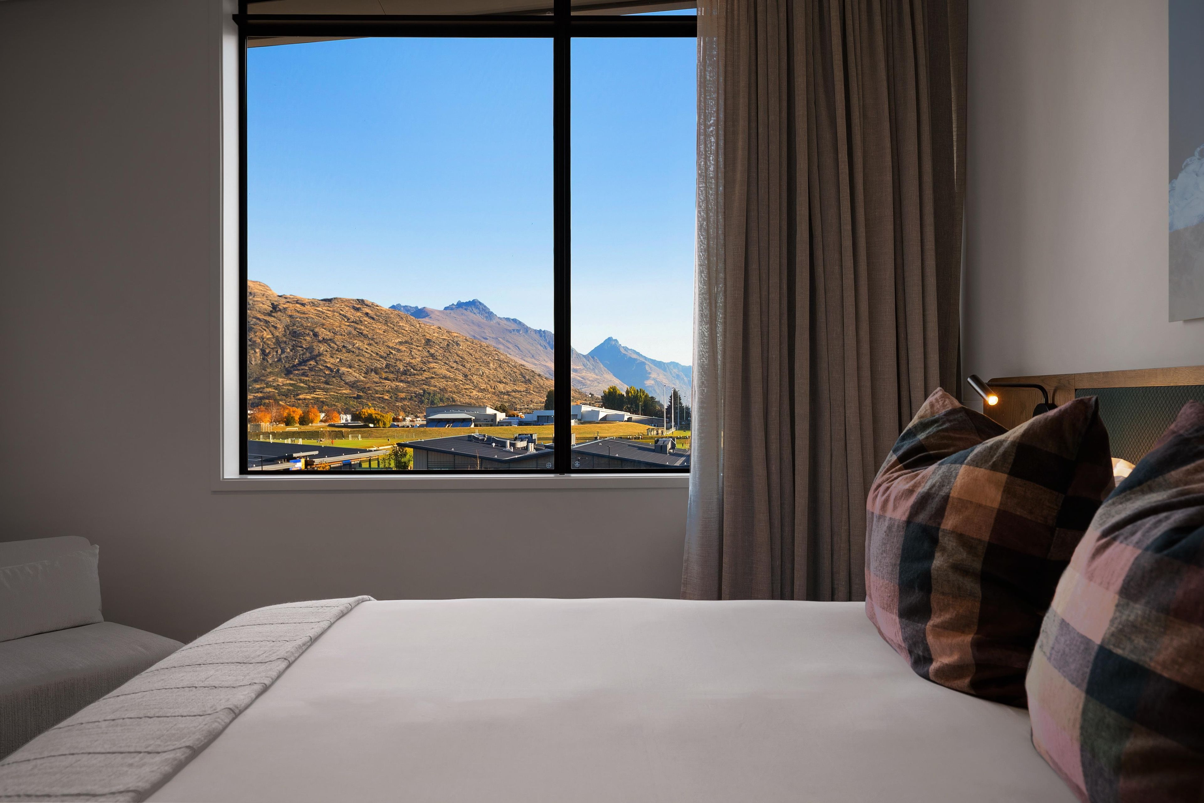 A hotel room with a large window, a bed, and a view of mountains.