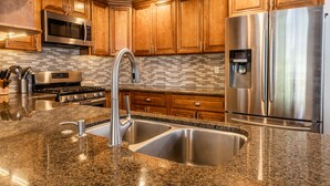 Una cocina moderna con encimeras de granito, electrodomésticos de acero inoxidable y armarios de madera.