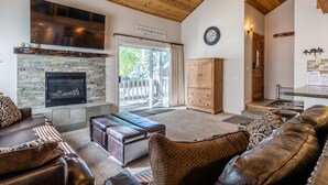 Una sala de estar acogedora con chimenea de piedra, sofás de cuero y techo de madera.