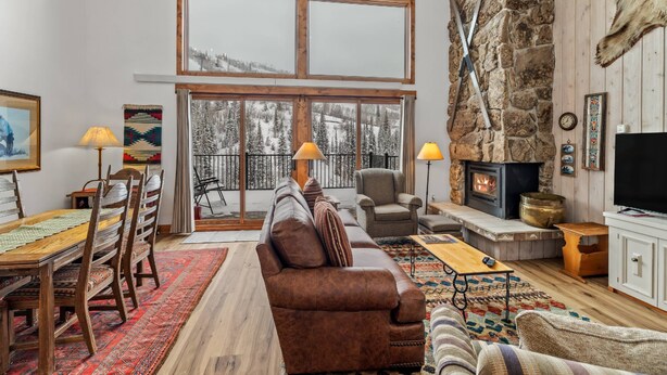 Ein gemütliches Wohnzimmer mit Kamin, großen Fenstern und einer Steinwand.