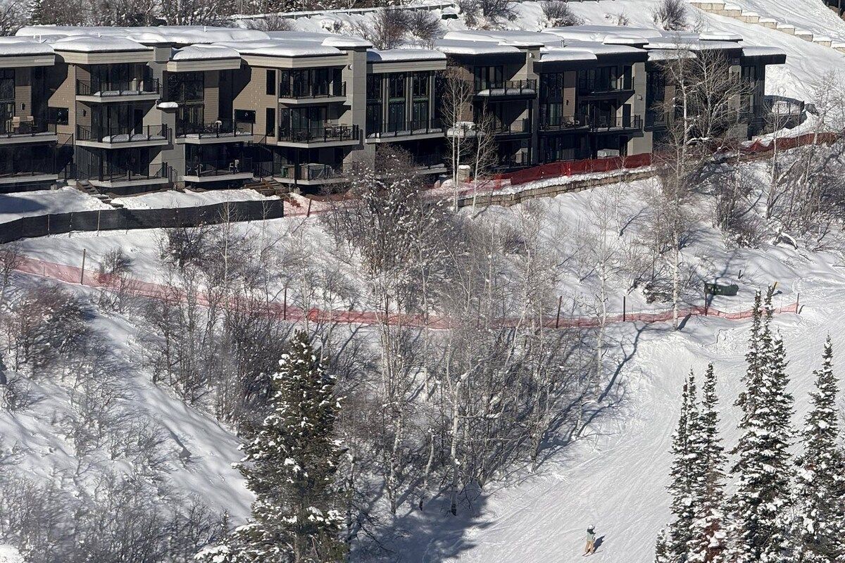 A modern ski resort with multi-story buildings, ski slopes, and snow-covered trees.
