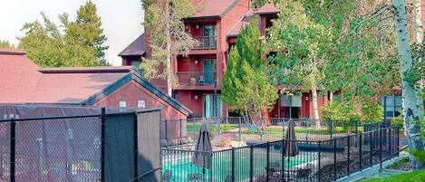 A residential building with a swimming pool, outdoor seating, and a fenced patio area.