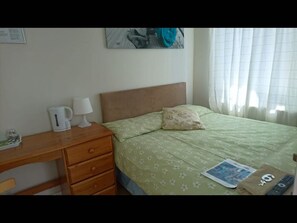 Cozy retreat with a comfortable bed, nightstand, and artwork.