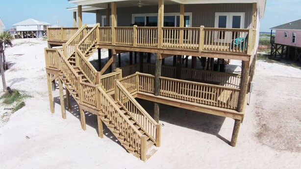 A two-story wooden beach house with a balcony, a staircase, and a metal roof. - Steps from the Beach! Water view from each bedroom! Great for multiple families! (Dauphin Island)