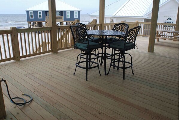 Una terraza de madera con mesa y sillas, con vistas al océano.