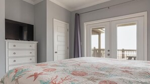A bedroom with a bed, dresser, and a balcony with a railing. - Steps from the Beach! Water view from each bedroom! Great for multiple families! (Dauphin Island)