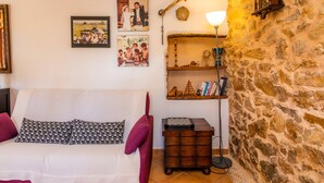 Ein gemütliches Zimmer mit einem weißen Sofa, einem Holztischchen mit Schachbrett und einer Steinwand.