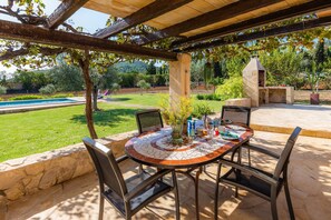 An outdoor patio with a mosaic table, chairs, and a stone oven. - Holiday Home "Ca Sa Padrineta" with Wi-Fi, Air Conditioning, Pool, Garden & Terrace (Capdepera)