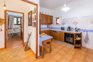 A kitchen with wooden cabinets, a sink, a stove, and a dining area with a table and chairs.