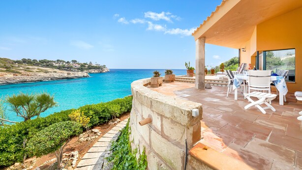 A coastal property with a patio, outdoor seating, and a view of the sea. - Villa Es Mirador with Sea View, Wi-Fi, A/C, Terrace & Garden; Parking Available (Cala Anguila-Cala Mendia)