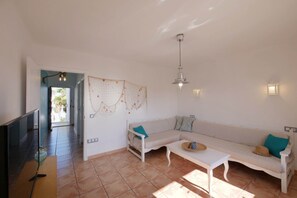 Un salon comprenant un canapé, une table basse, un téléviseur et un élément décoratif mural.